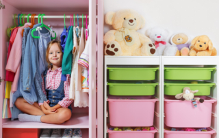 Child sitting in her neatly organized and decluttered closet.