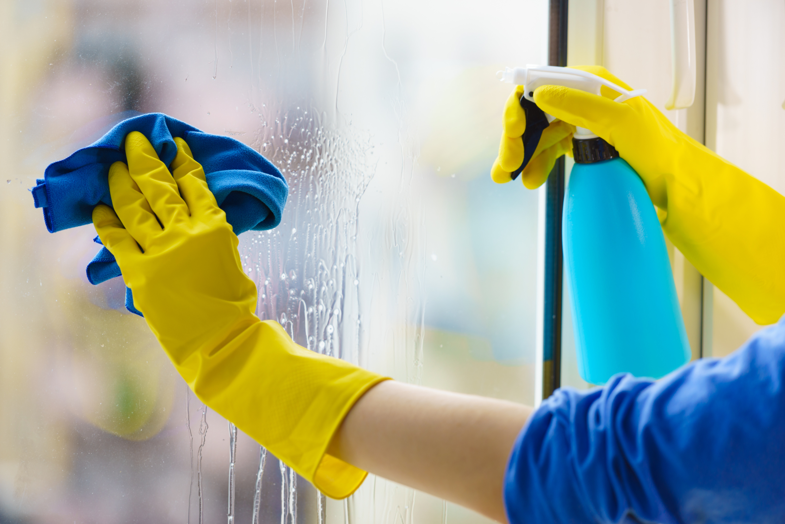 Gloved hand cleaning window rag and spray.